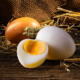 drei gekochte Eier auf Stroh und dunklem Holzhintergrund